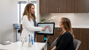 dentist at Complete Dental Works showing a patient how drinks that damage tooth enamel cause erosion over time